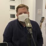 John Davis with face mask in front of microphone